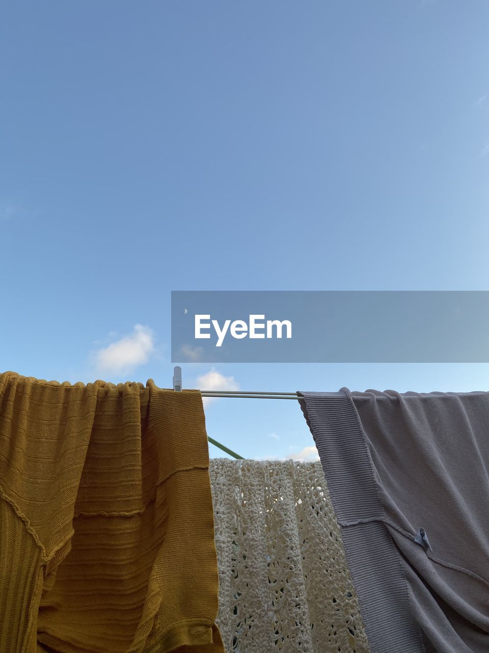 LOW ANGLE VIEW OF CLOTHES DRYING AGAINST BUILDINGS