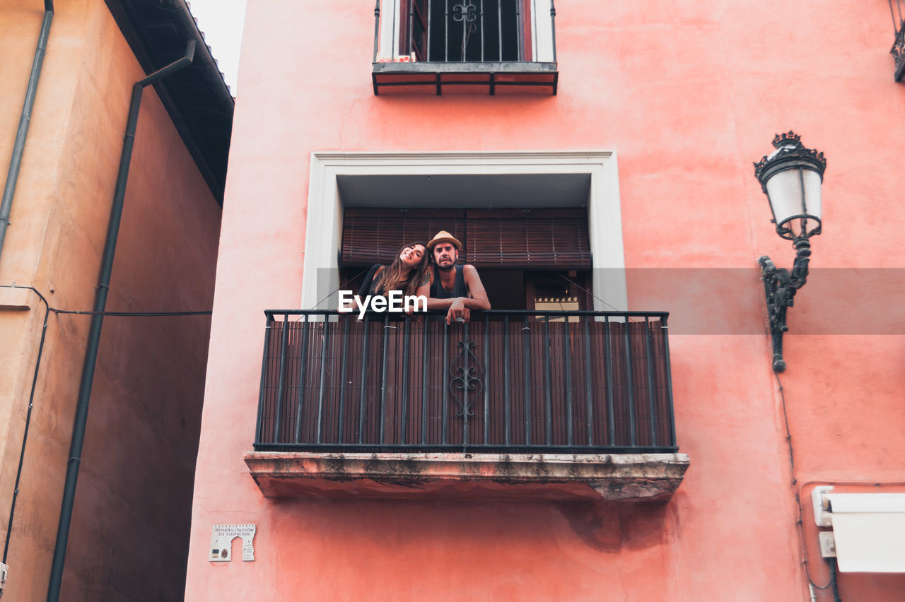 Portrait of young man with girlfriend standing at balcony