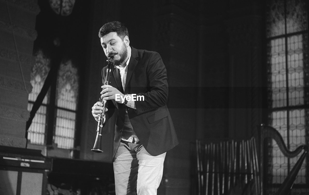 Man playing clarinet while standing at studio