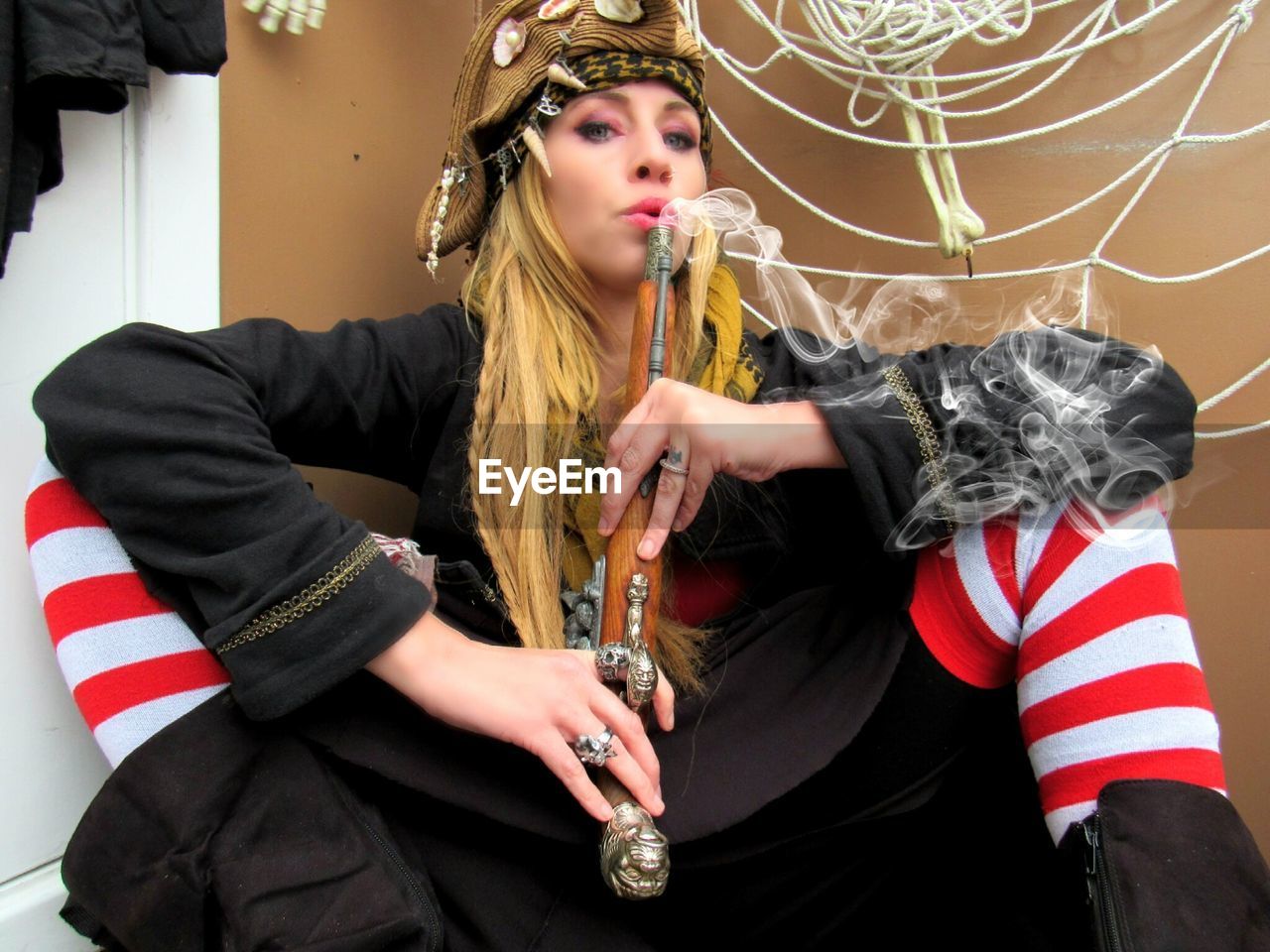 Portrait of female pirate blowing smoke emitting from gun