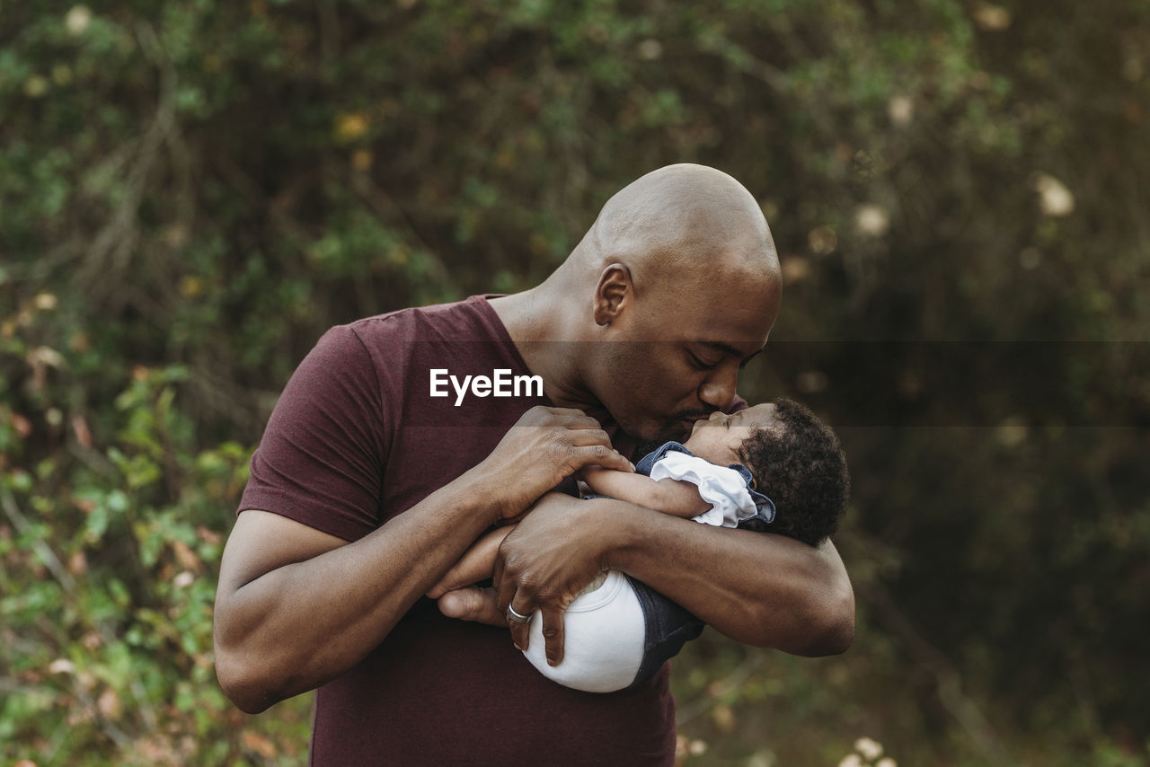 Close up happy father holding and kissing newborn girl outside