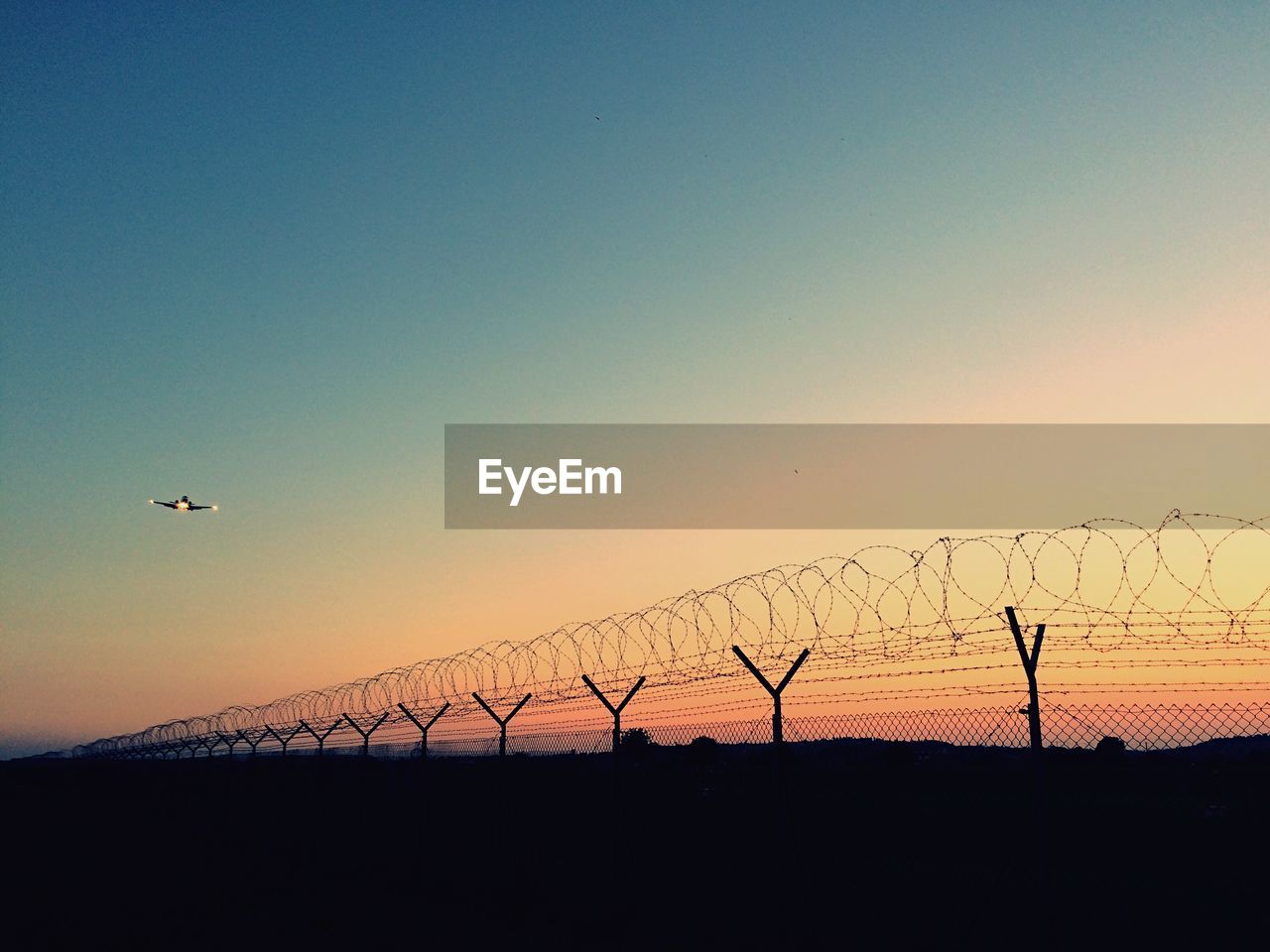 SILHOUETTE BIRDS FLYING OVER LANDSCAPE AGAINST CLEAR SKY