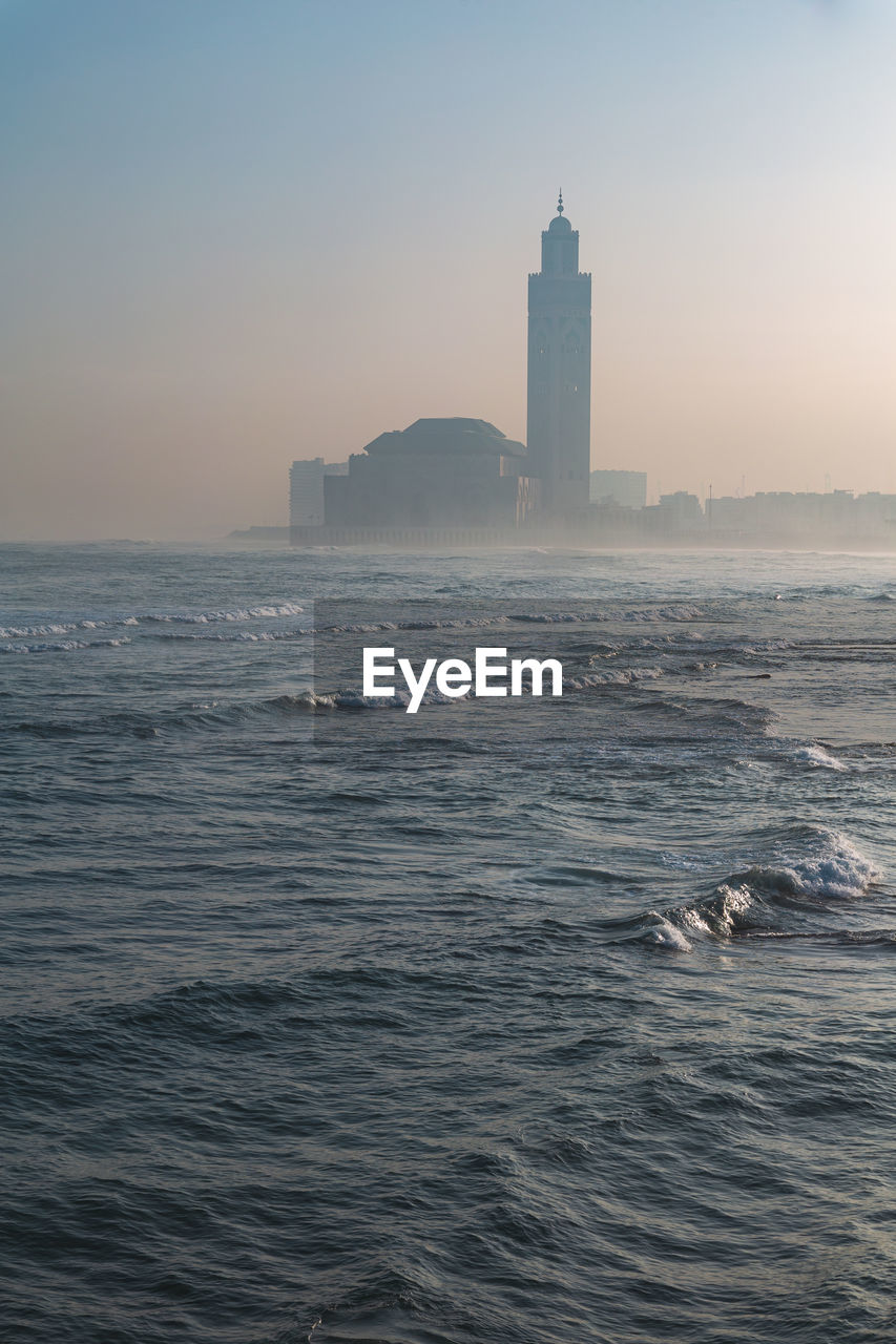 Hassan 2 mosque by sea against sky during sunset