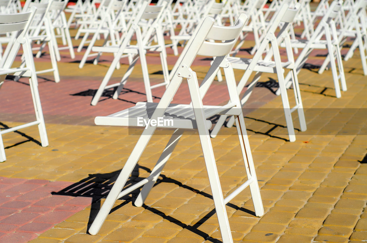 Folding chairs are arranged on recreation area. empty folding wooden chairs in a public square