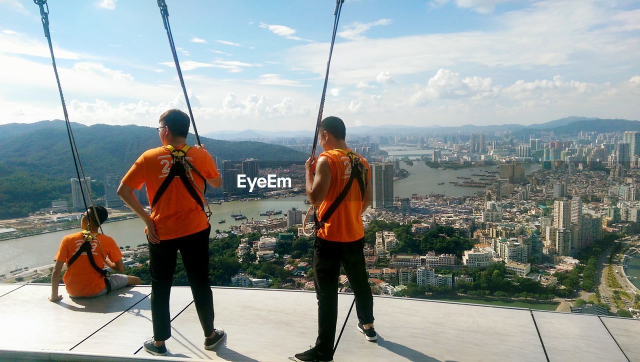 REAR VIEW OF MEN LOOKING AT CITYSCAPE