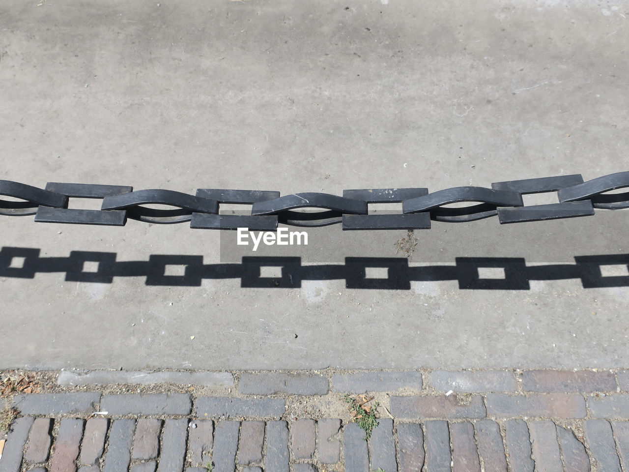 A chain with shadow forming the partition between the sidewalk and the road