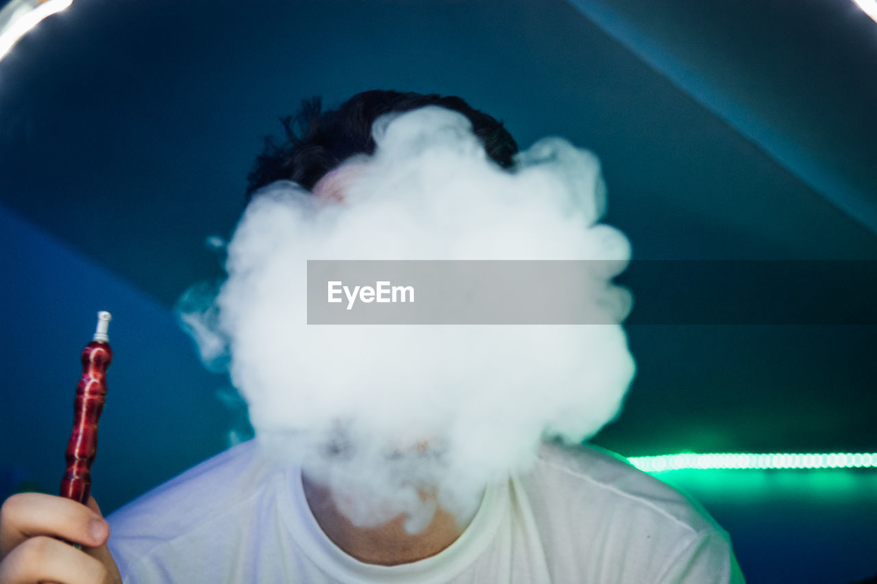 Close-up of young man smoking in club