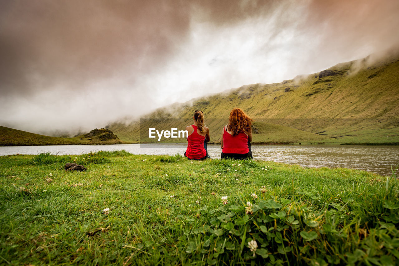 Two friends sitting in nature, landscape, caldera of corvo, azores.