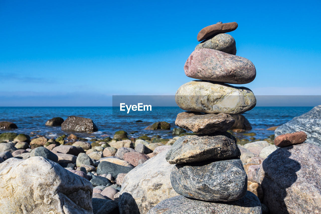 STACK OF ROCKS AT SEA SHORE AGAINST SKY