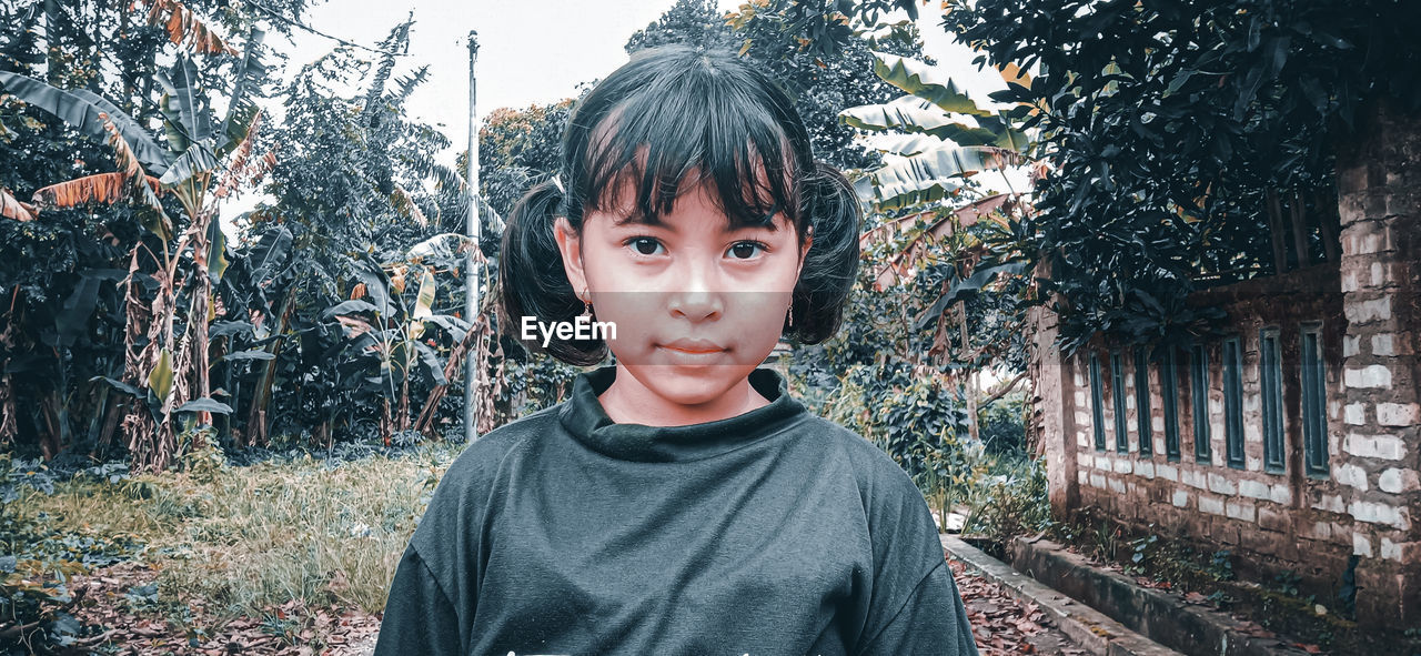 PORTRAIT OF BOY STANDING AGAINST TREE