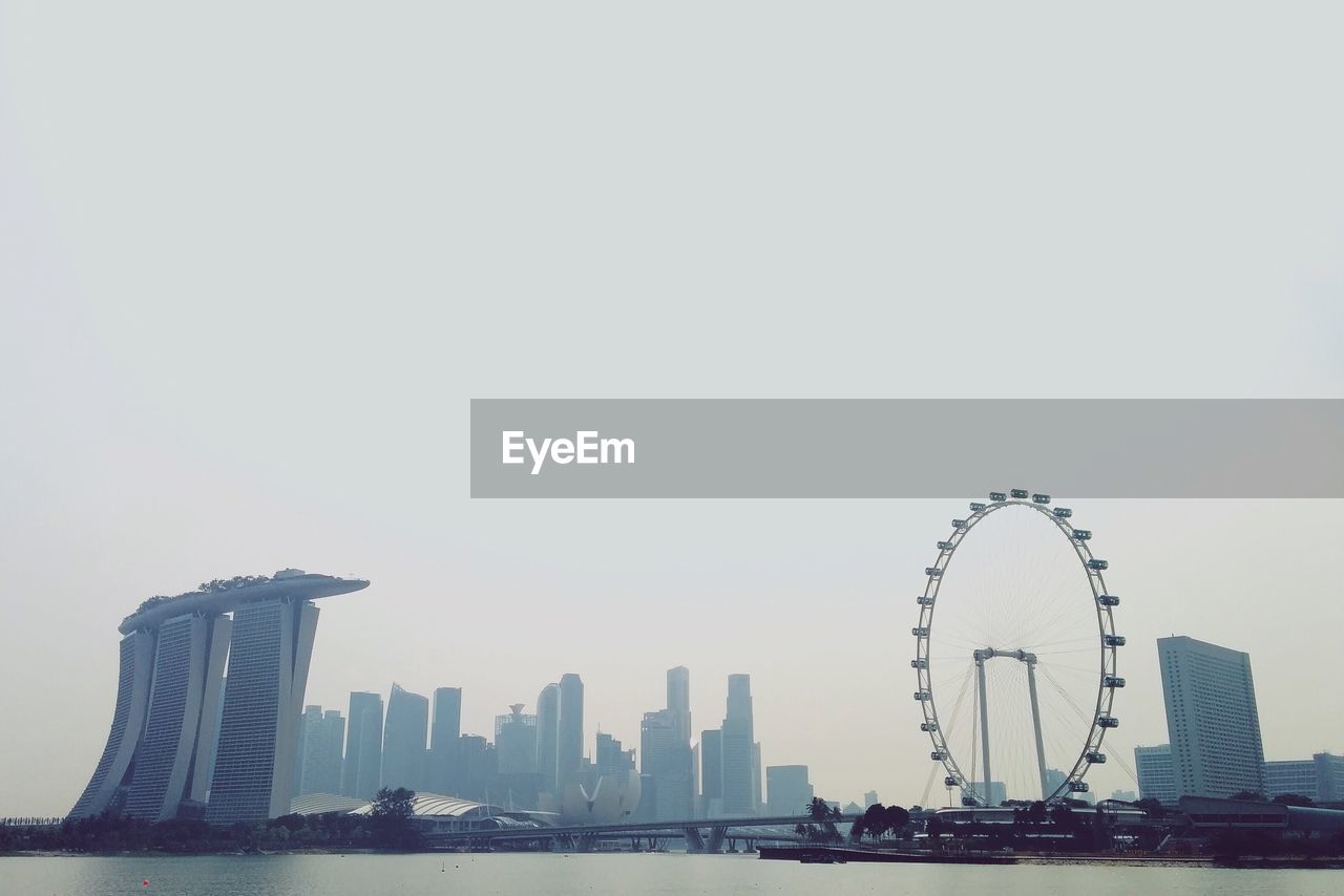 Marina bay sands and ferris wheel against clear sky