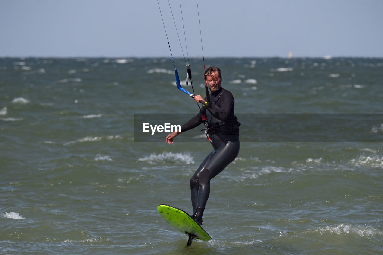 rear view of woman jumping in sea against sky