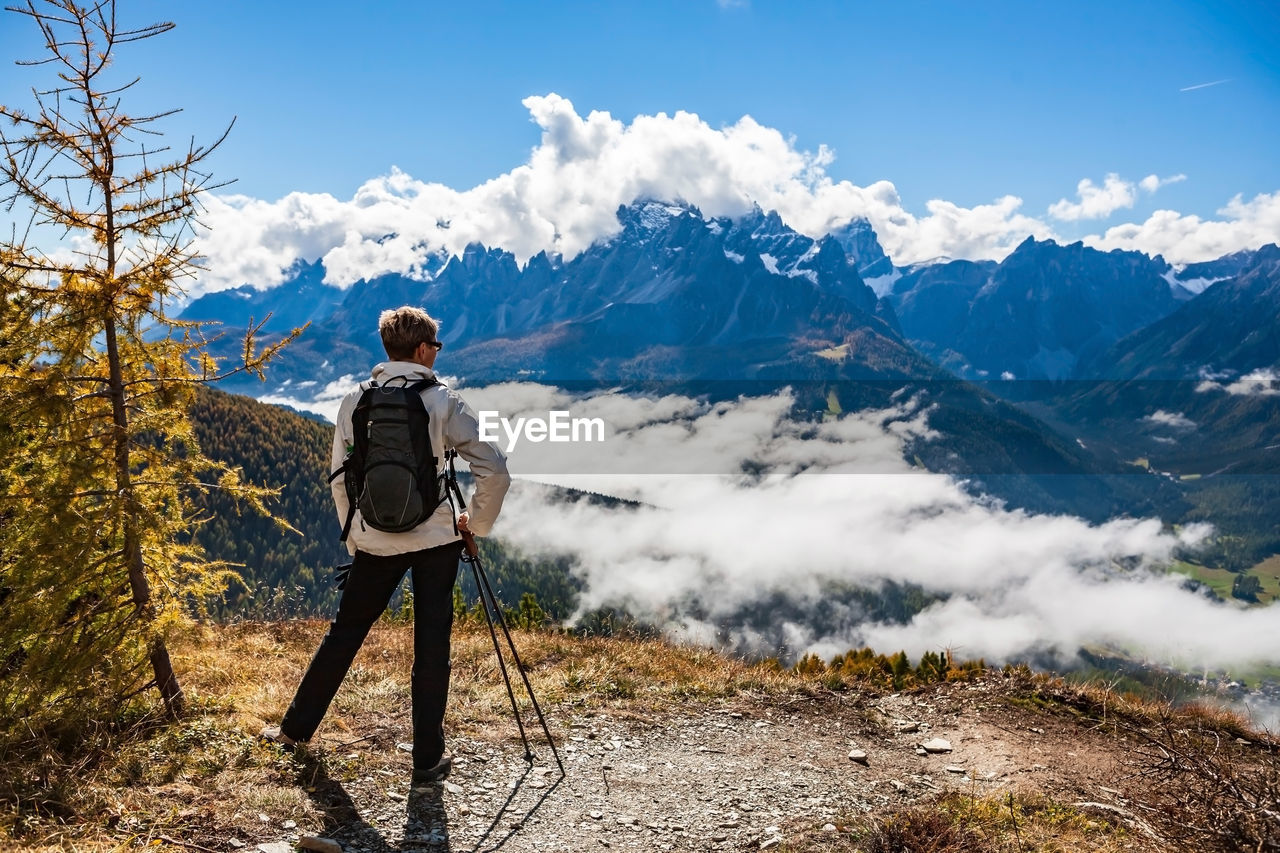 Rear view of man standing on mountain against sky