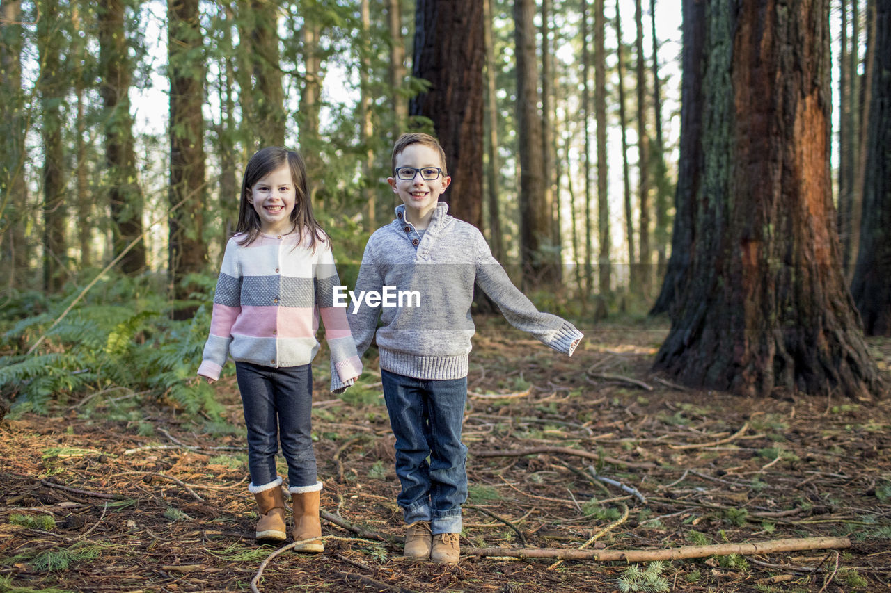 Brother and sister playing in the forest.