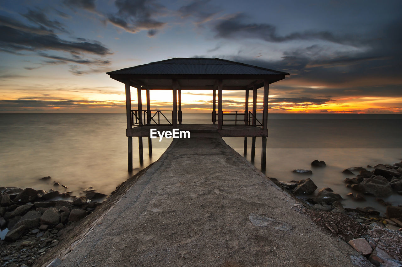 Lifeguard hut on beach against sky during sunset