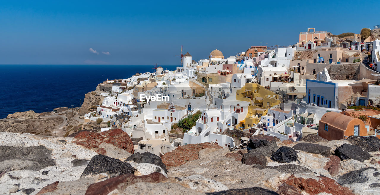 Houses by sea against blue sky