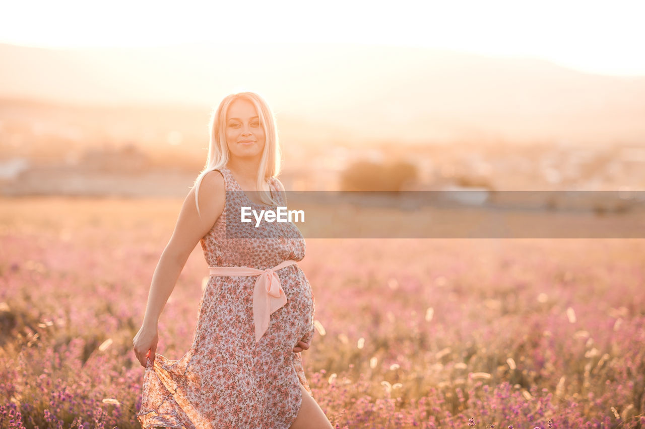 Smiling pregnant woman standing on field