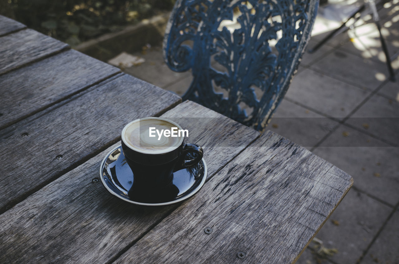 drink, cup, wood, food and drink, mug, blue, table, coffee, refreshment, coffee cup, high angle view, crockery, hot drink, day, outdoors, no people, saucer, seat, freshness, still life, cafe, nature, focus on foreground, bench, sunlight, food
