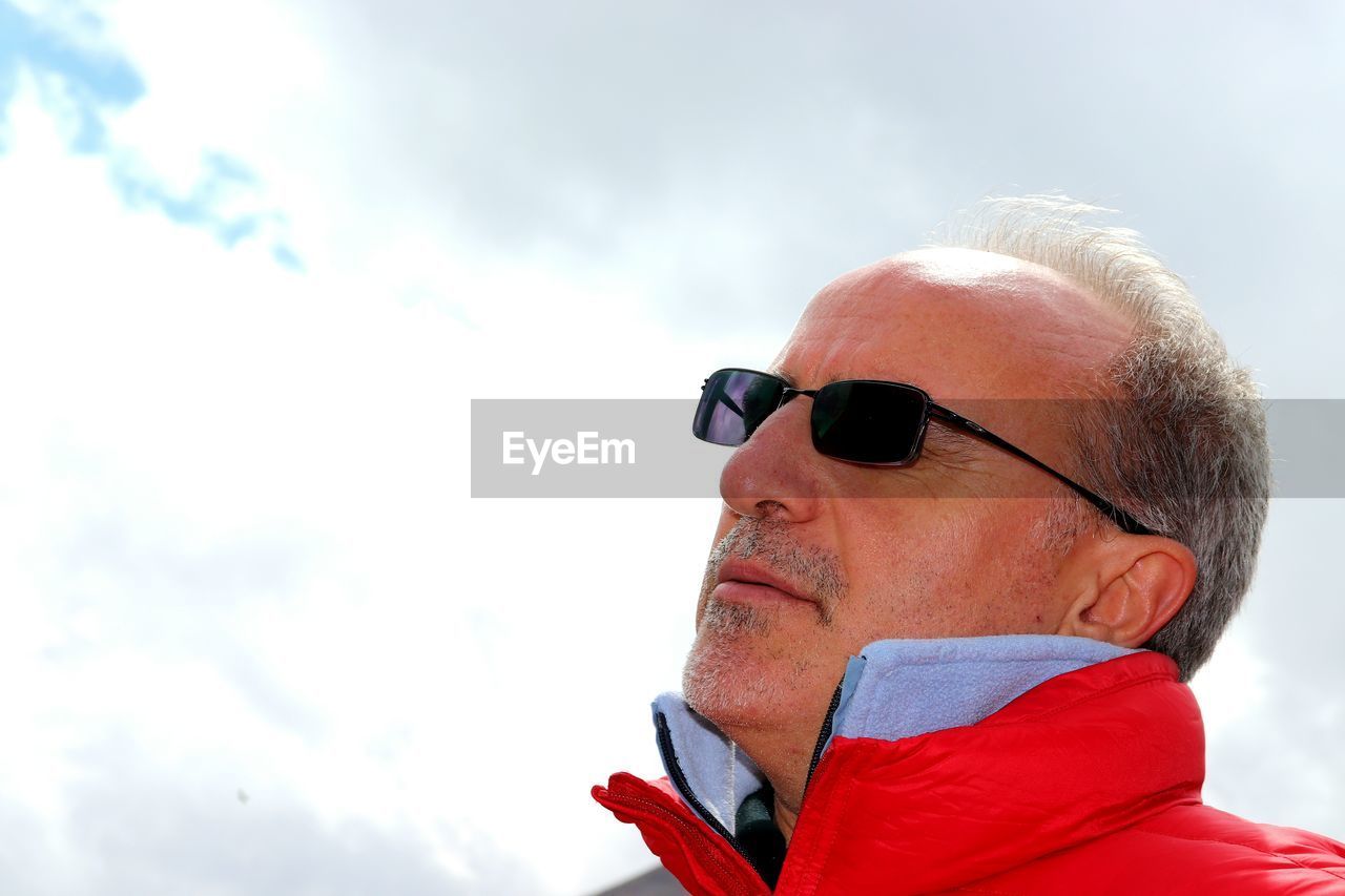 CLOSE-UP PORTRAIT OF MAN WITH SUNGLASSES AGAINST SKY