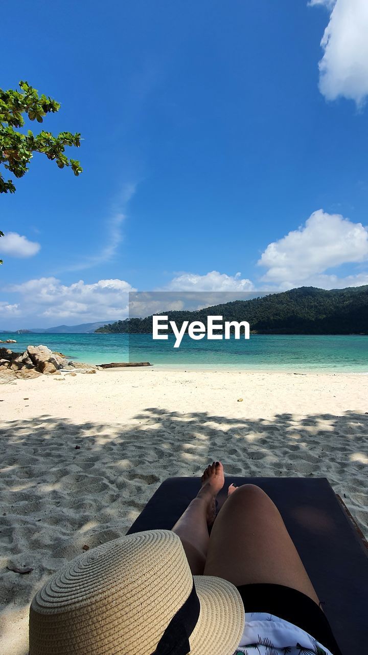 LOW SECTION OF PERSON RELAXING ON BEACH