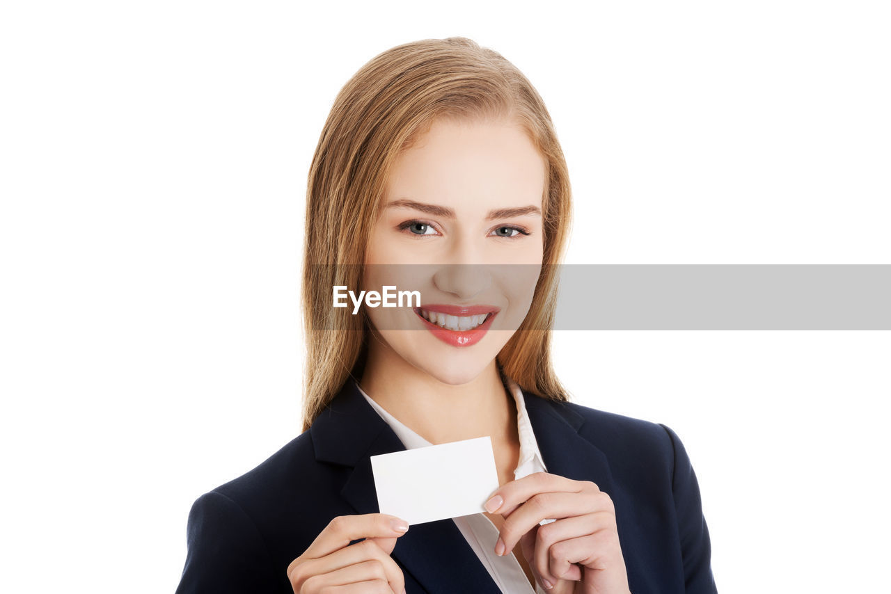 Portrait of smiling businesswoman holding card against white background