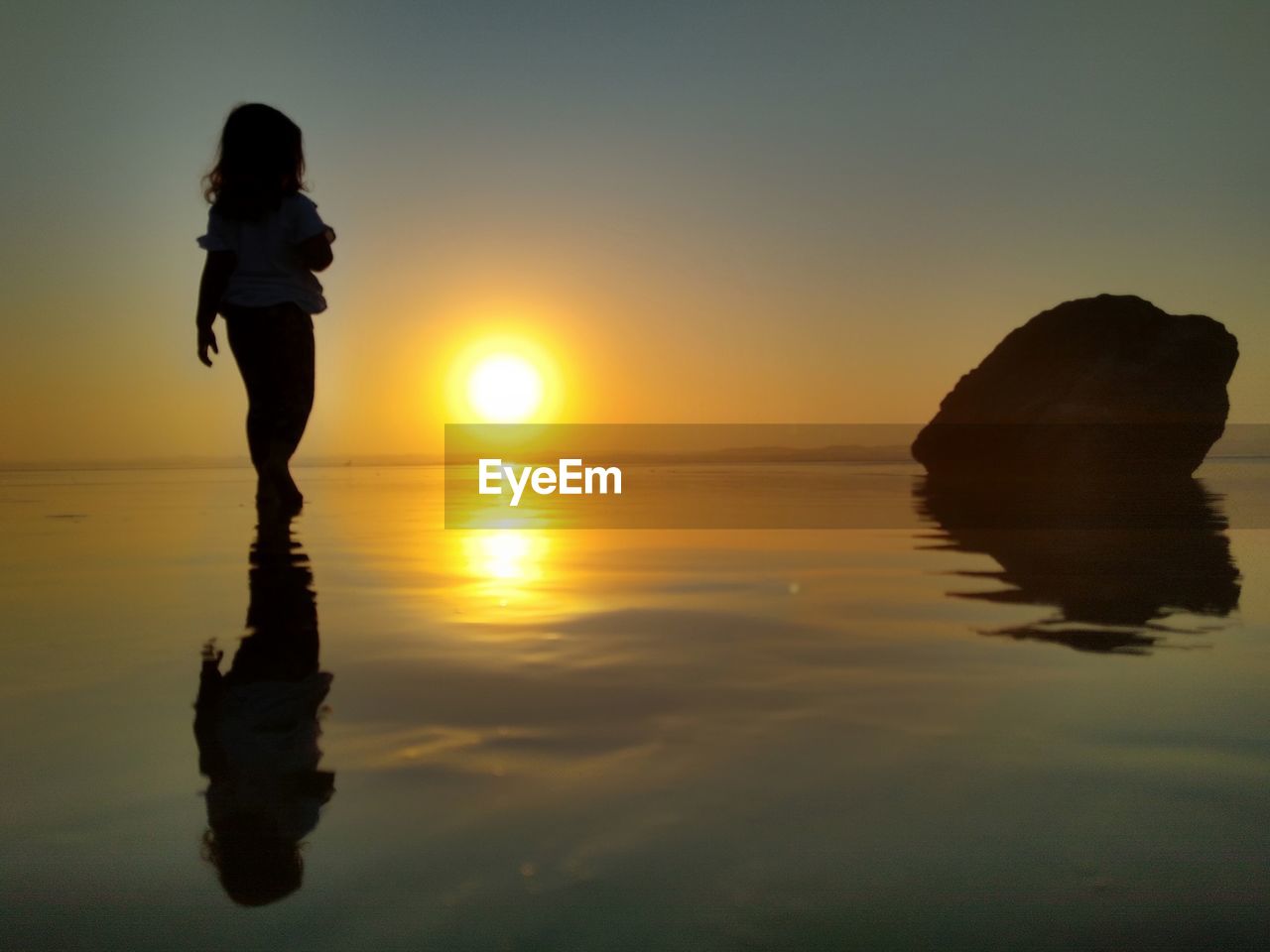 MAN STANDING ON BEACH DURING SUNSET