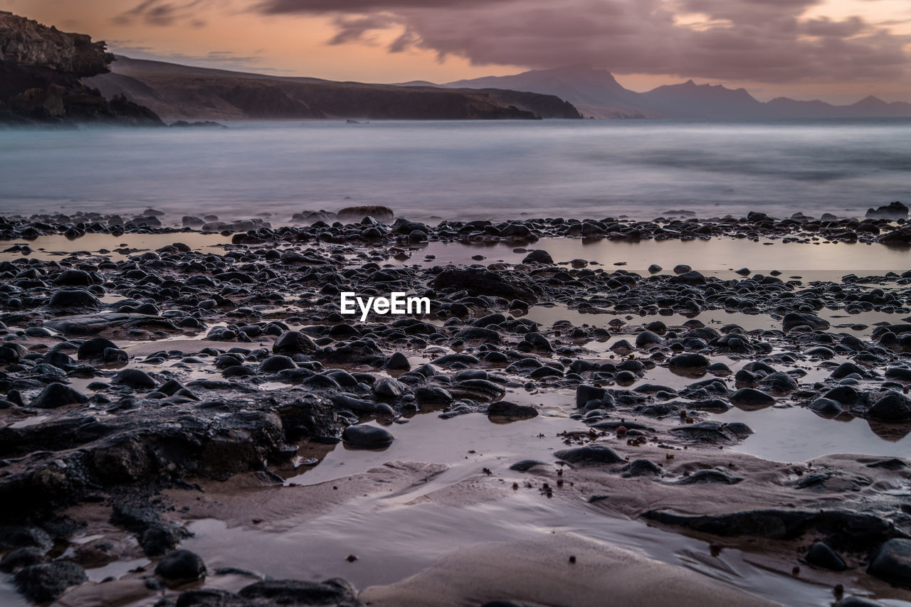 SCENIC VIEW OF BEACH AGAINST SKY DURING SUNSET