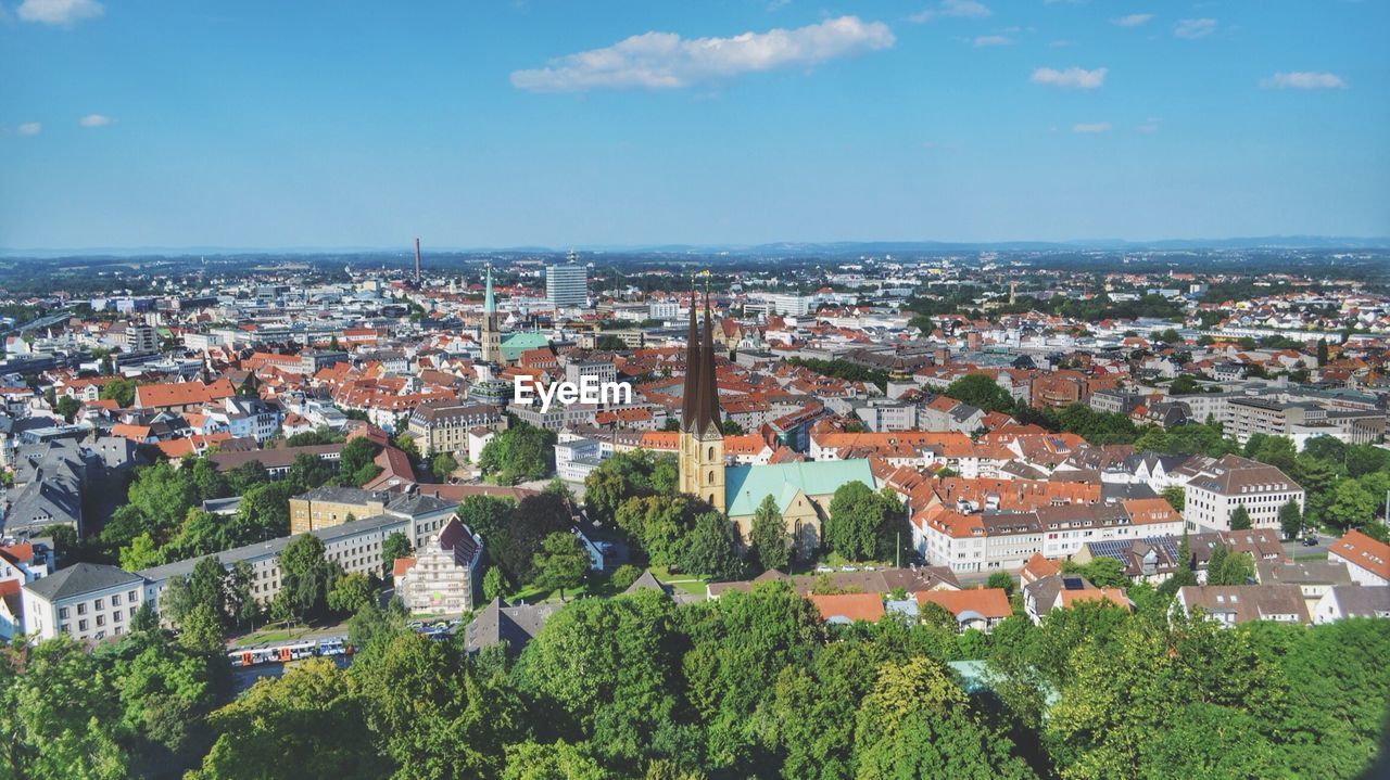 High angle view of trees and buildings against blue sky