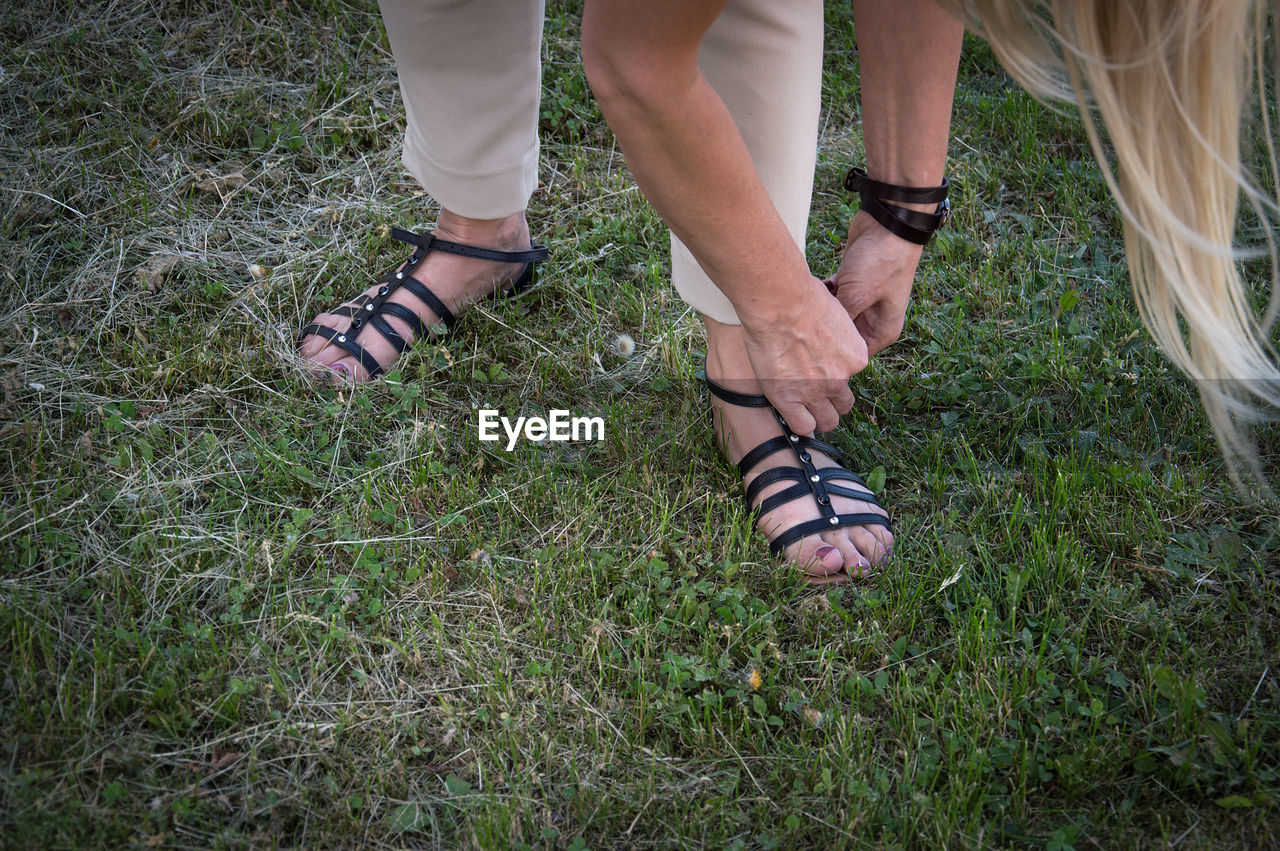 Low section of woman wearing sandal on grass