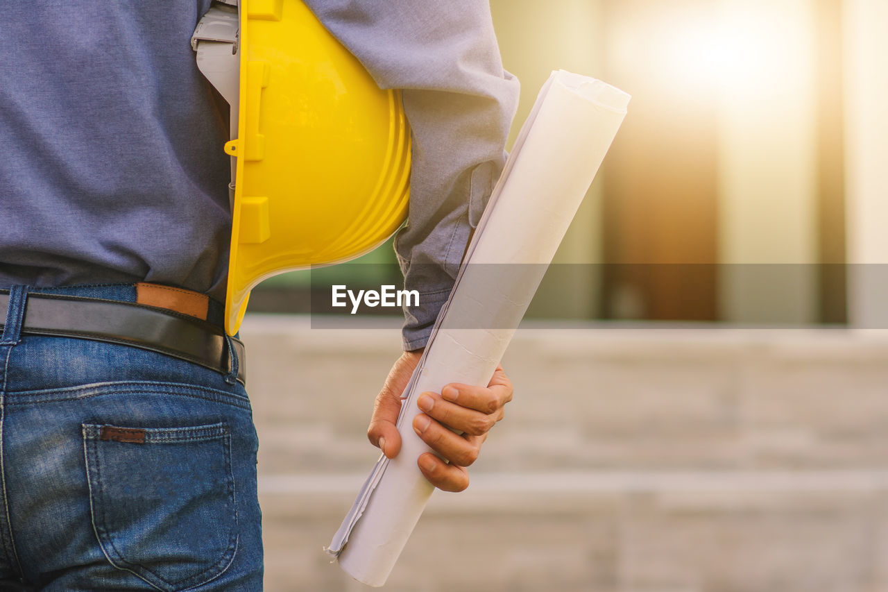 MIDSECTION OF MAN WORKING WITH UMBRELLA