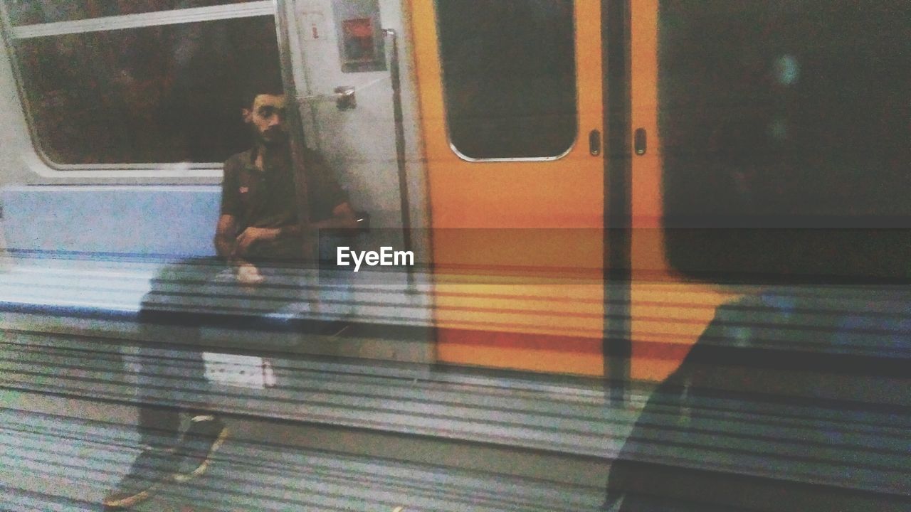 TRAIN ON RAILROAD STATION PLATFORM SEEN THROUGH WINDOW