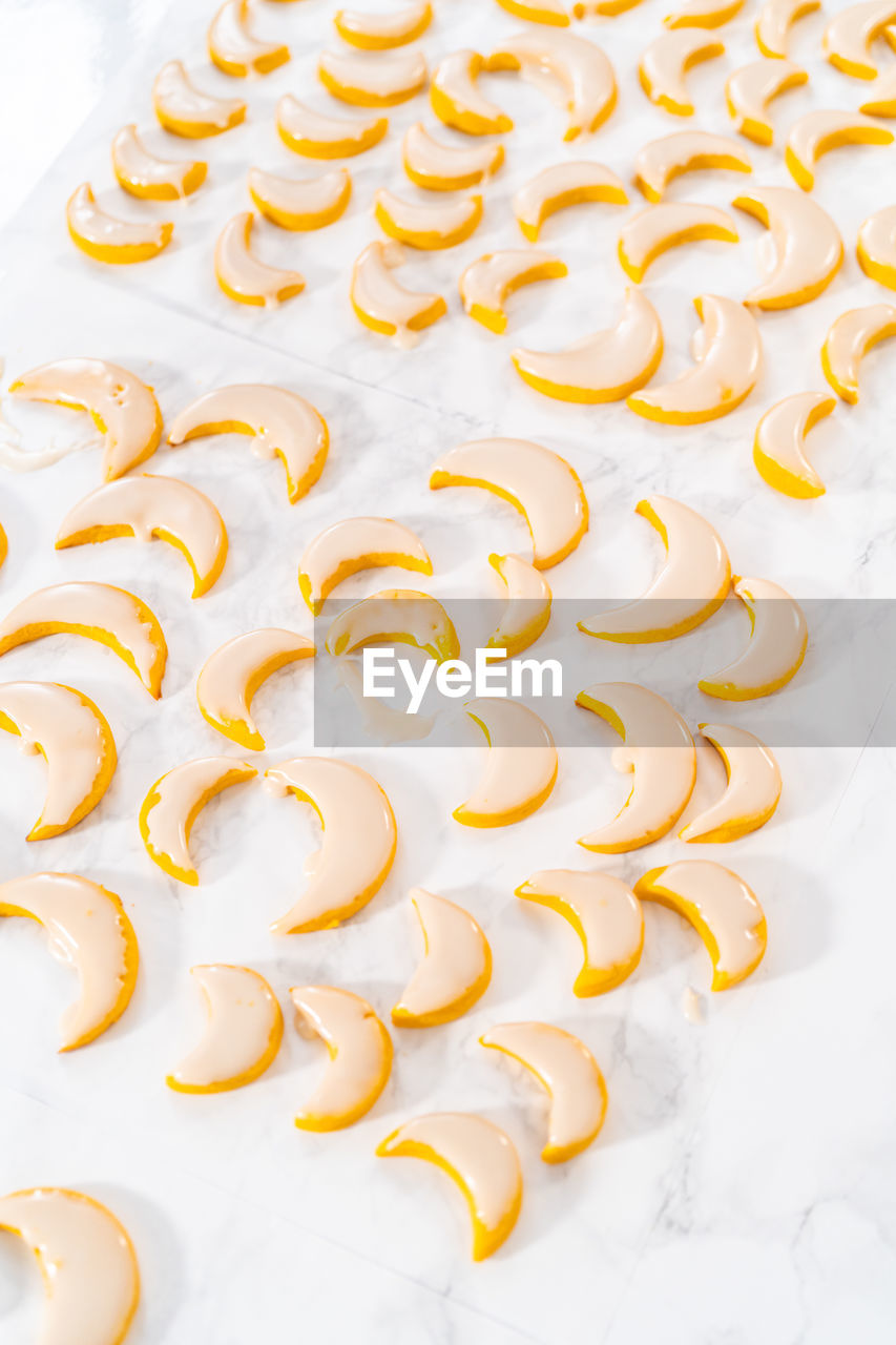 food, food and drink, icing, large group of objects, no people, indoors, freshness, dessert, yellow, petal, high angle view, in a row, white, still life, sweet food, abundance, healthy eating, studio shot, white background