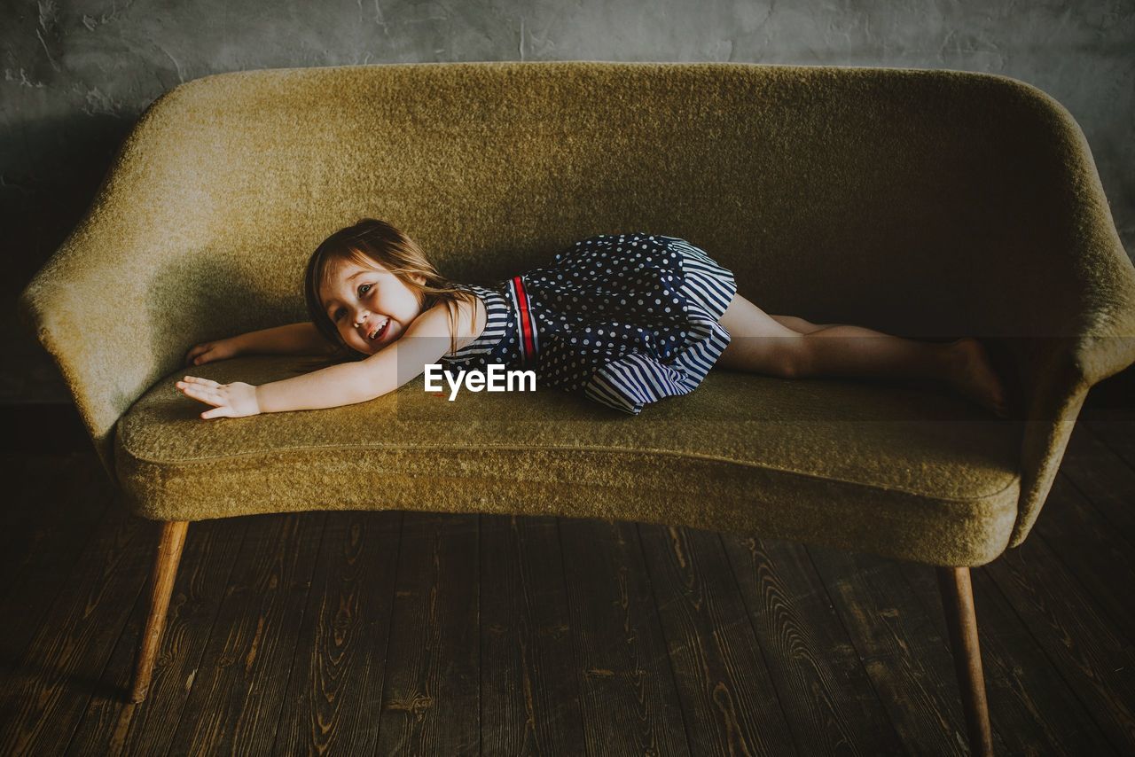 High angle view of girl lying on sofa at home