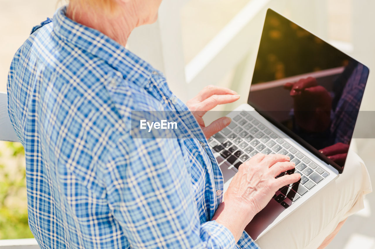 Unrecognizable senior woman using laptop for distance learning education outdoor