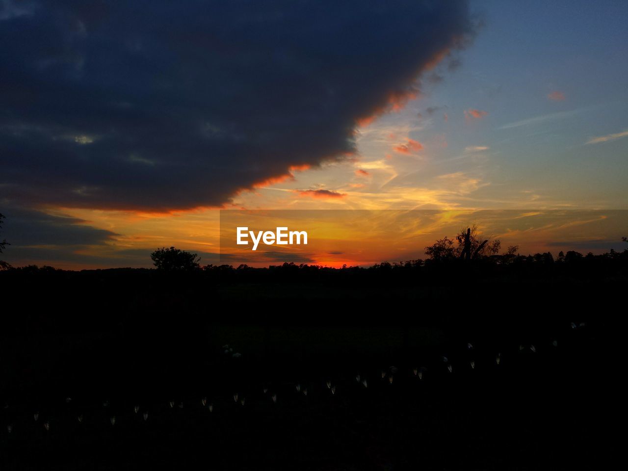 Scenic view of silhouette field against cloudy sky