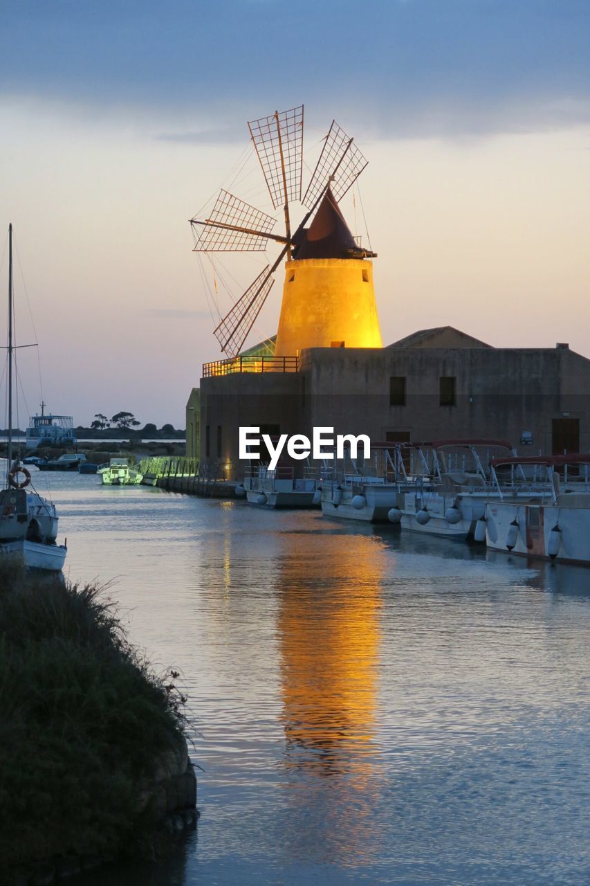 Reflection of traditional windmill on canal at sunset