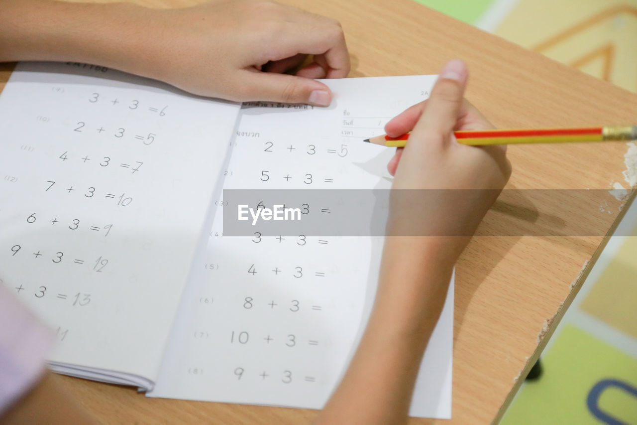 HIGH ANGLE VIEW OF CHILD HAND HOLDING PAPER WITH TEXT