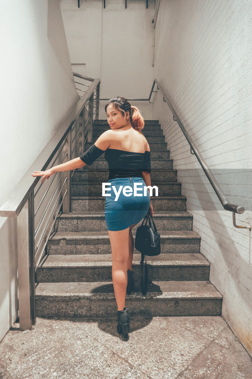 YOUNG WOMAN STANDING ON STAIRCASE