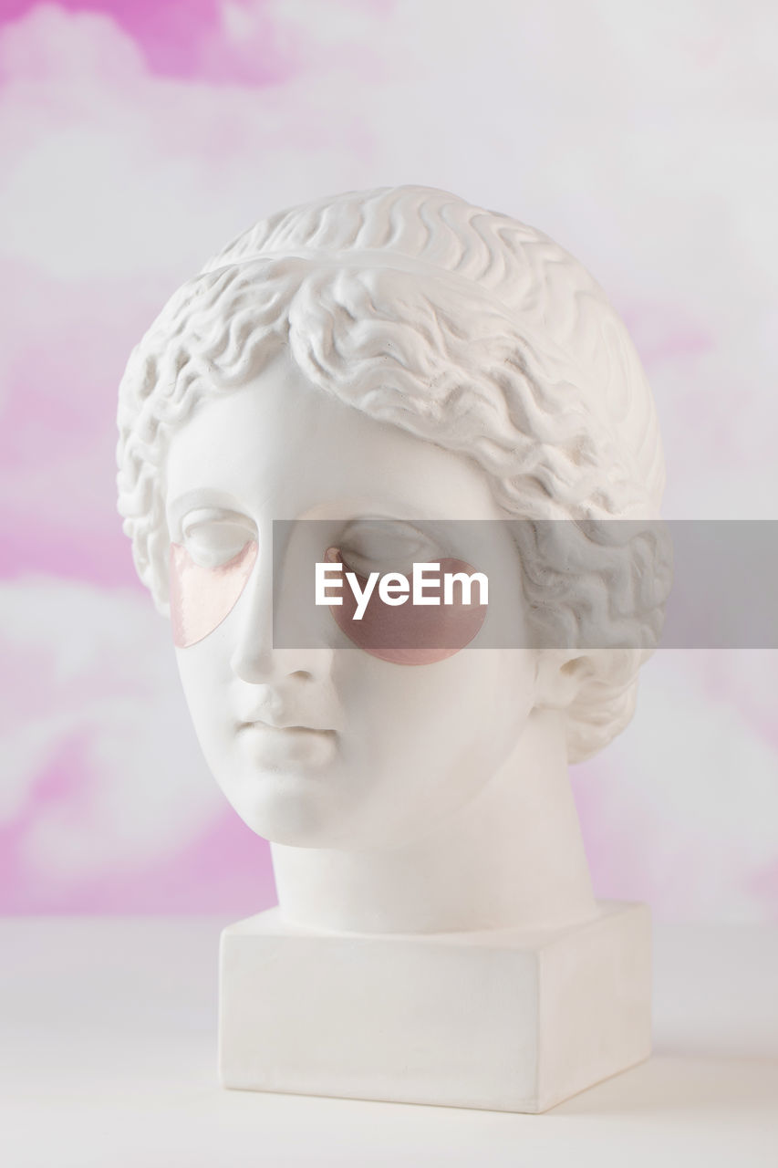 Hydrogel pink patches on the plaster head of aphrodite on a pink background. beauty concept.