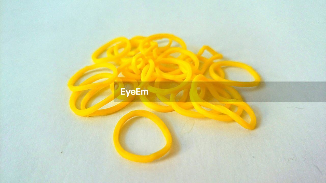 Close-up of yellow rubber bands over white background