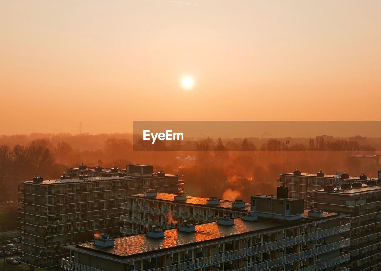 Buildings by clear sky at sunset