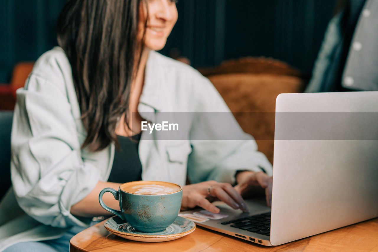 Young business woman drinking coffee while working on a laptop in a cafe.