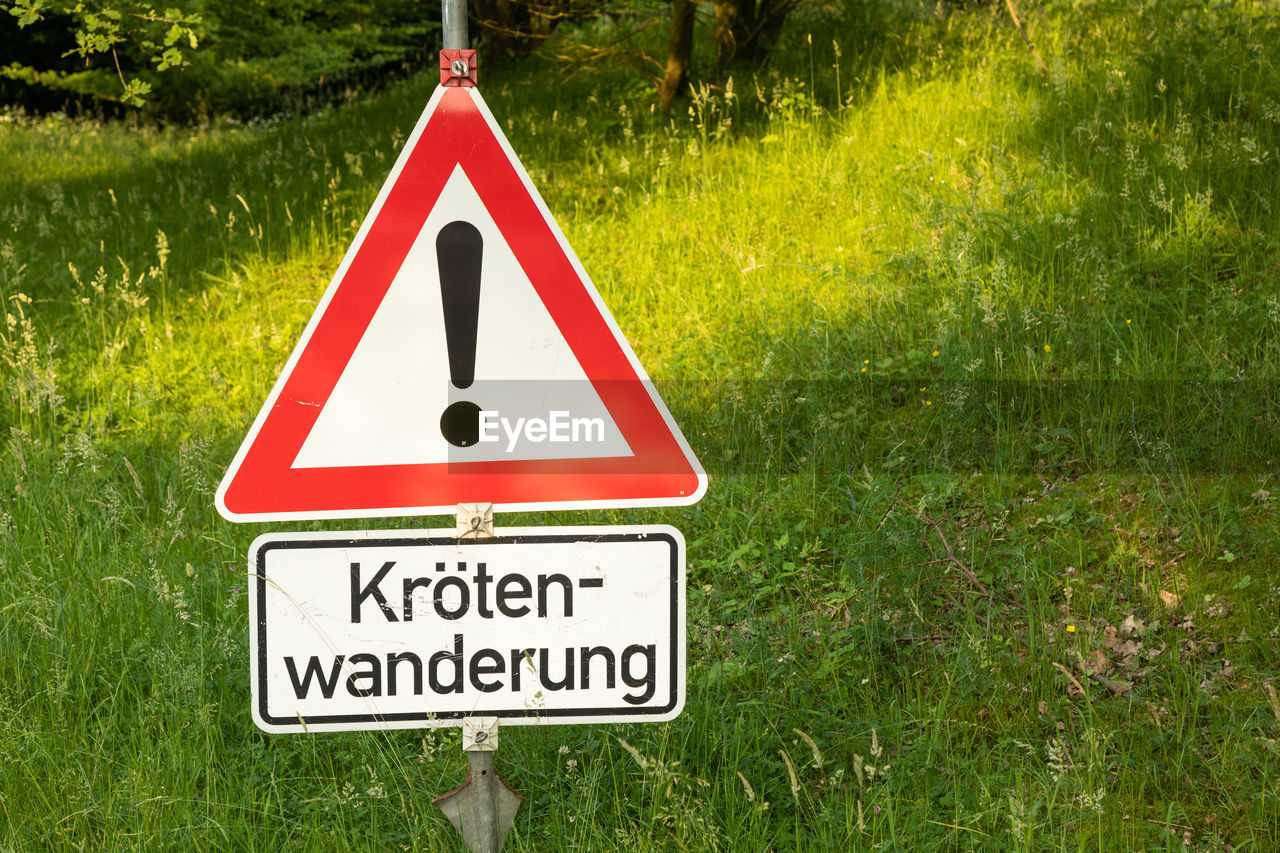 CLOSE-UP OF ROAD SIGN ON GREEN GRASS