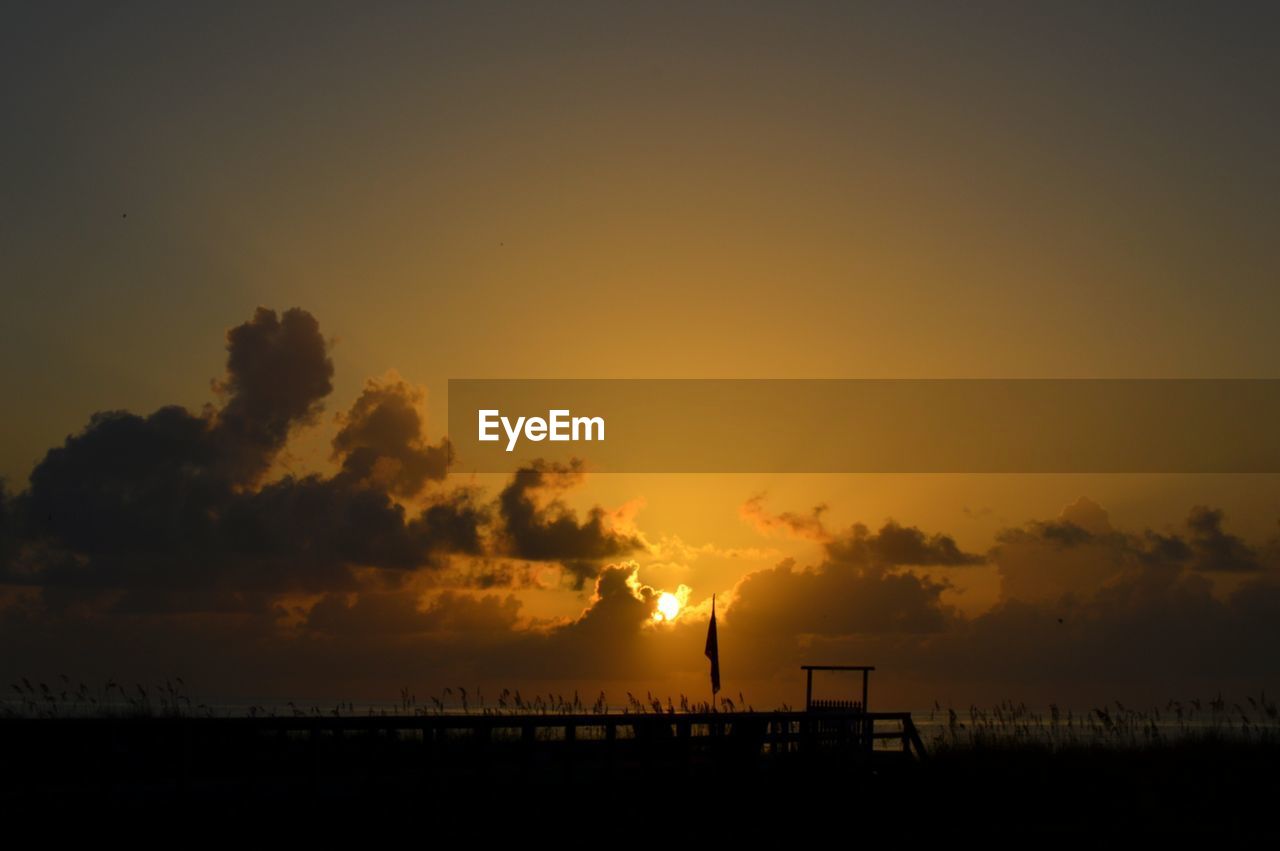 Silhouette beach against sky during sunset