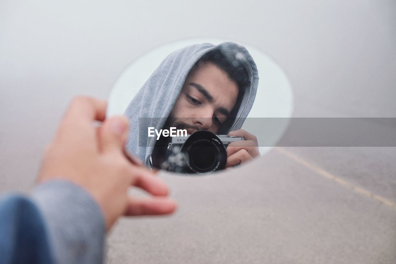 PORTRAIT OF MAN HOLDING CAMERA