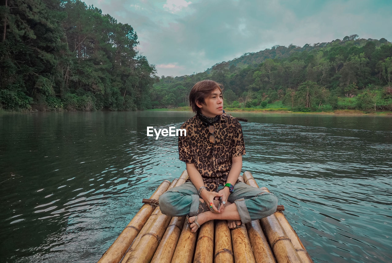 portrait of woman sitting on pier over lake