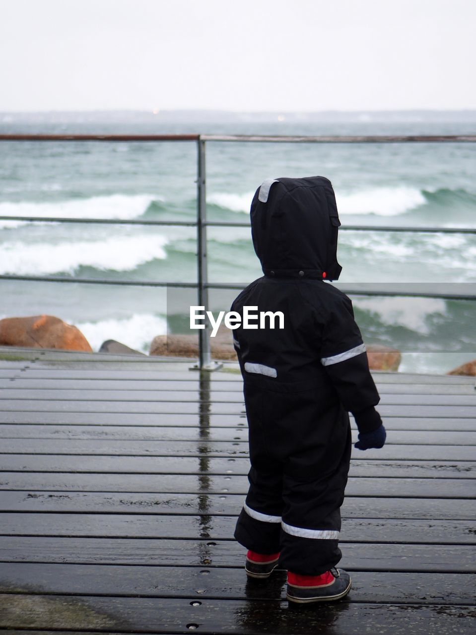 Rear view of girl looking at sea from pier against sky
