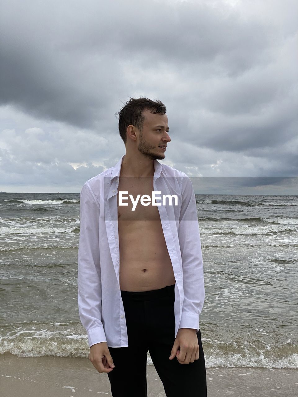 YOUNG MAN STANDING ON BEACH