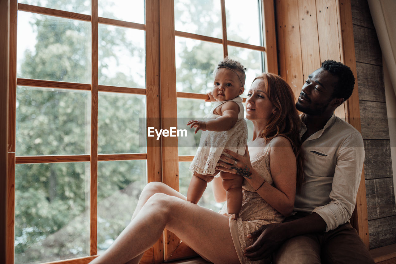 Young couple sitting on window at home