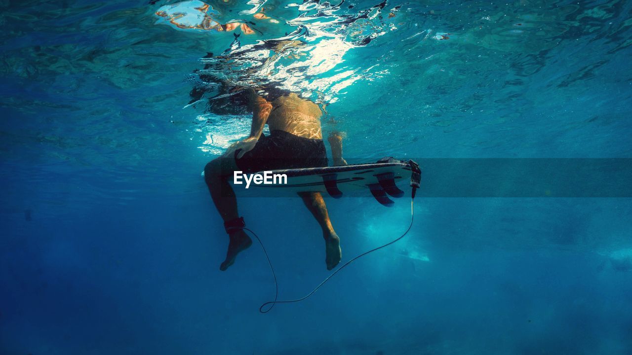 Low section of shirtless man surfing undersea